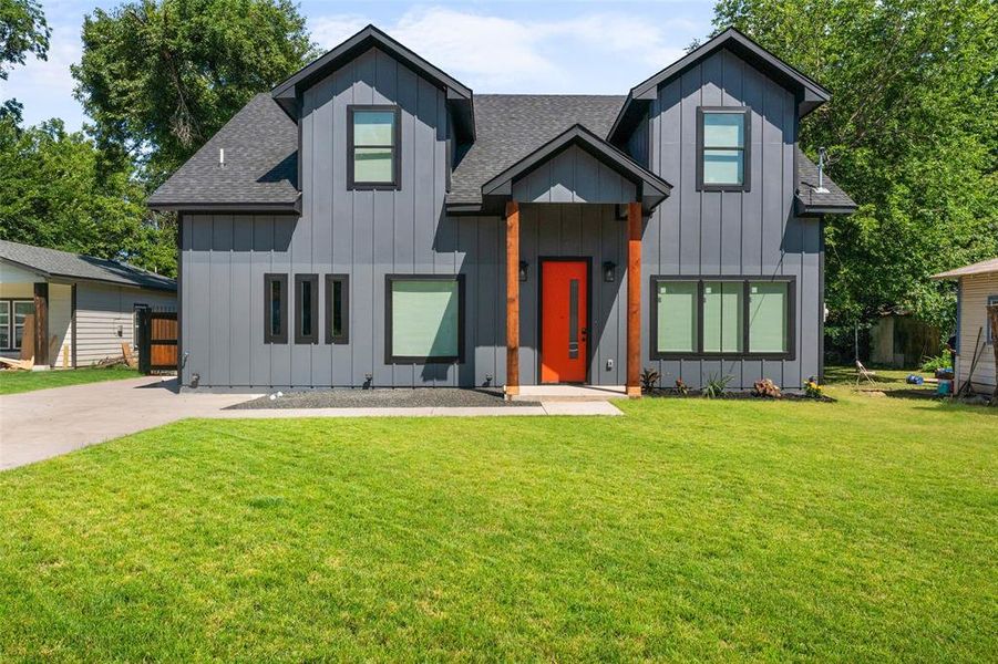 Modern inspired farmhouse with board and batten siding, a shingled roof, and a front yard