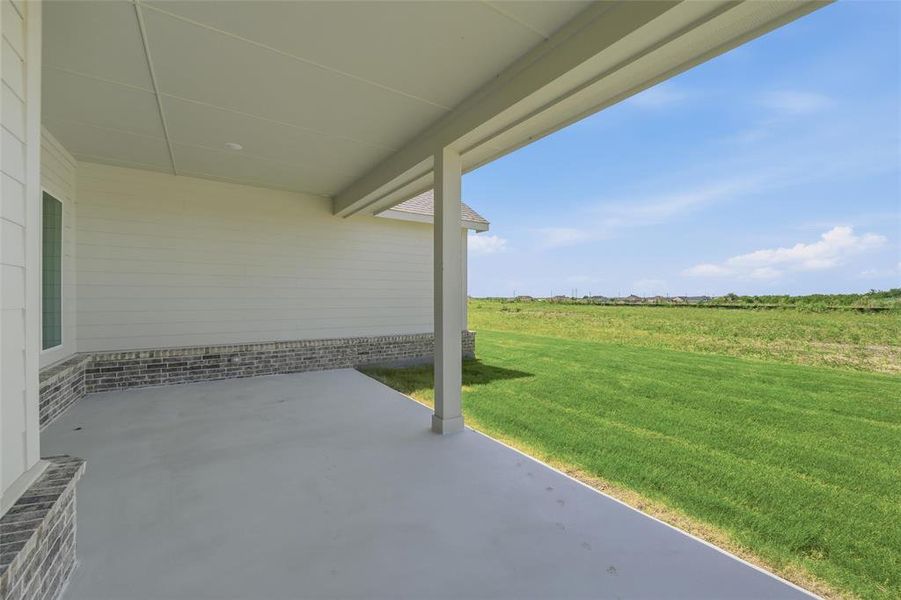 Covered patio with a concrete surface, white siding, and a brick veneer accent wall Covered patio with a concrete surface, white siding, and a brick veneer accent wall