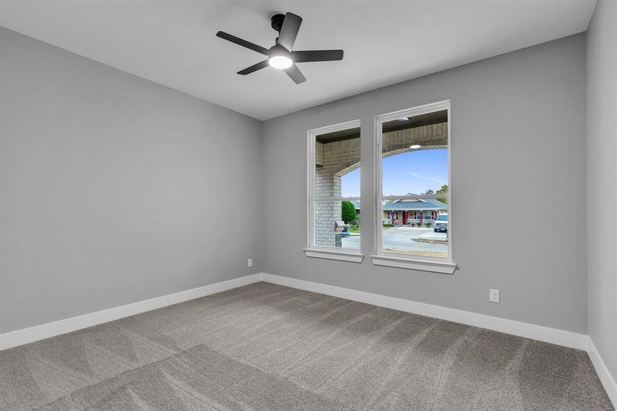 Carpeted empty room featuring ceiling fan