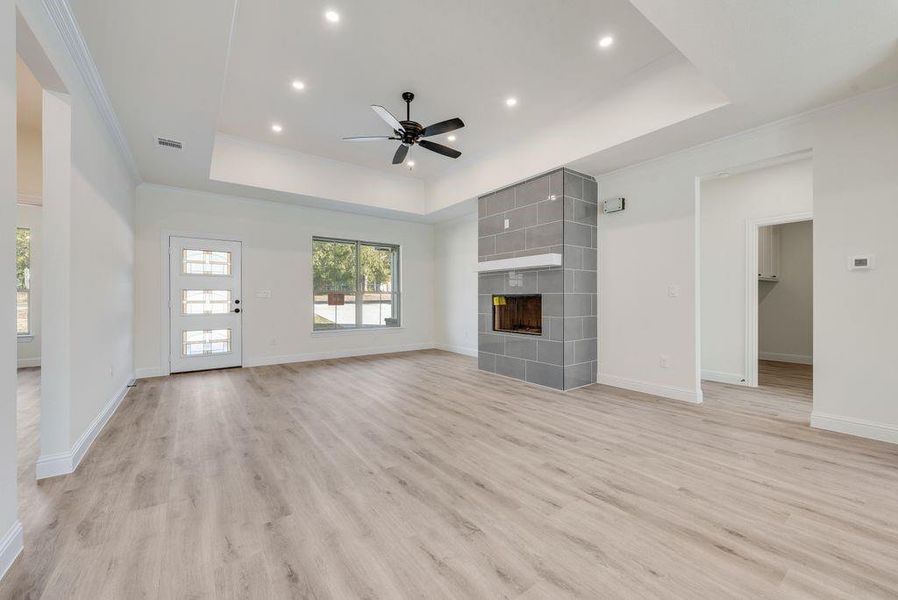 Unfurnished living room with light hardwood / wood-style flooring, a tile fireplace, and a raised ceiling