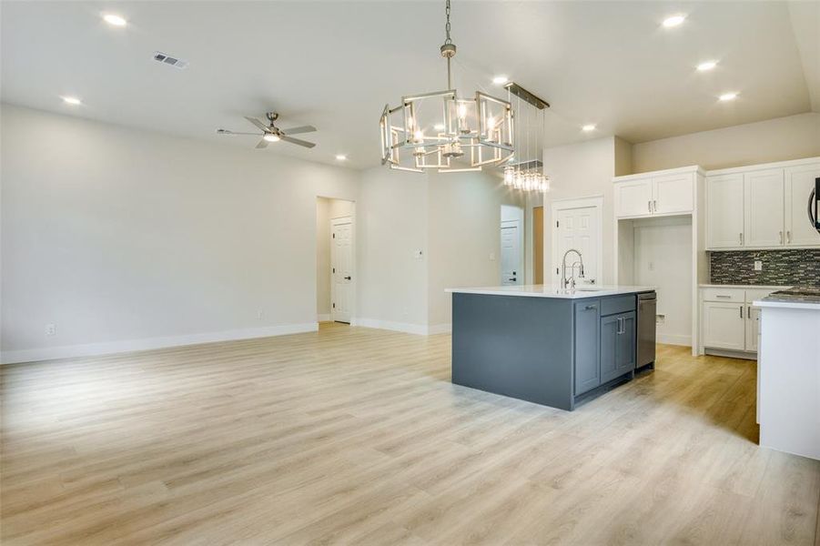 Kitchen featuring white cabinetry, ceiling fan with notable chandelier, open floor plan, recessed lighting, and light wood-style flooring