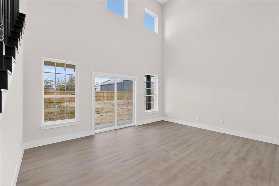 Room with plenty of natural light, wood finished floors, and a high ceiling Room with plenty of natural light, wood finished floors, and a high ceiling