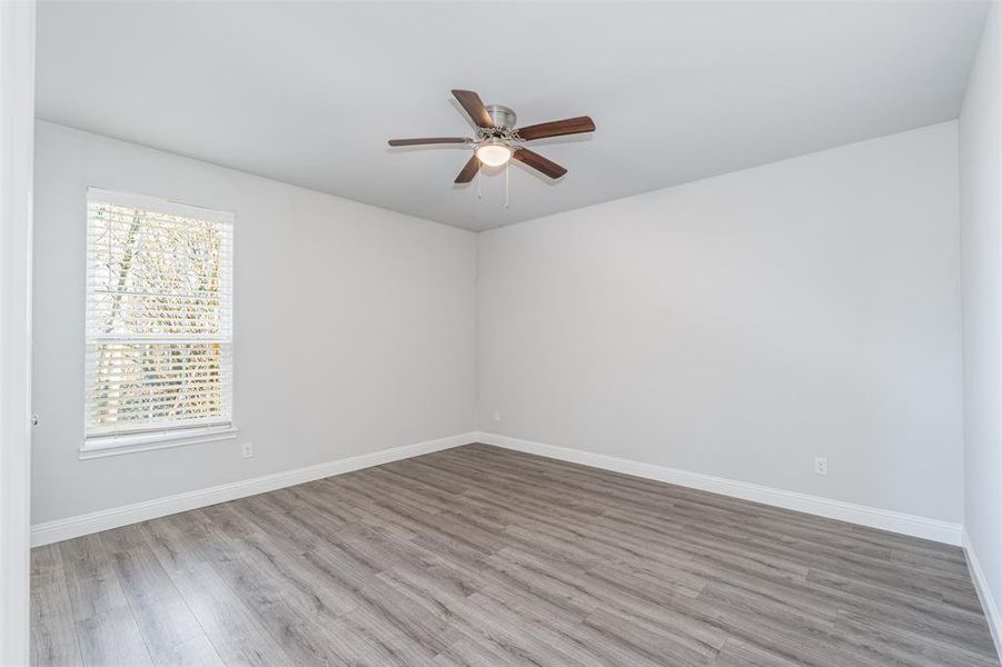 Spare room featuring ceiling fan, baseboards, and wood finished floors