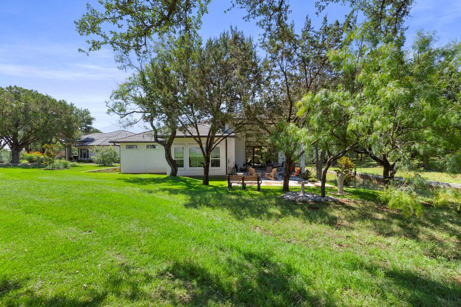 A spacious yard surrounds a single-story residence, offering ample outdoor living space and mature trees.