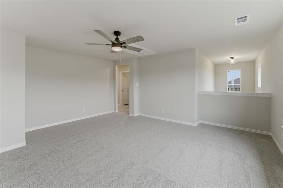 Spacious carpeted room featuring a ceiling fan with integrated lighting, neutral wall tones, and white trim