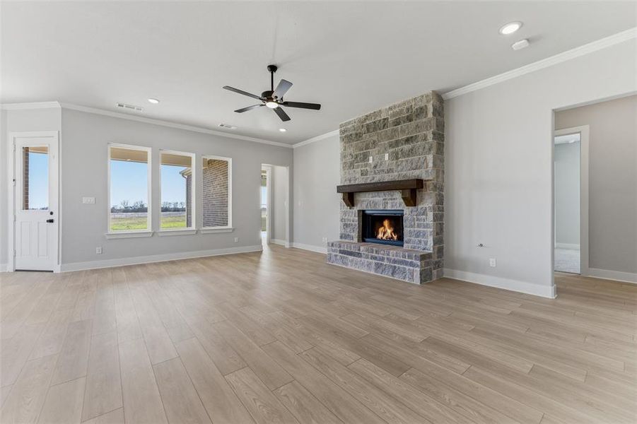 Unfurnished living room with crown molding, a fireplace, a ceiling fan, light wood-type flooring, and recessed lighting