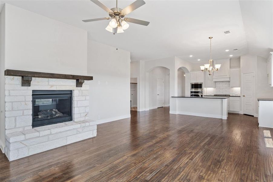 Unfurnished living room featuring a fireplace, a chandelier, dark wood finished floors, arched walkways, and recessed lighting Unfurnished living room featuring a fireplace, a chandelier, dark wood finished floors, arched walkways, and recessed lighting