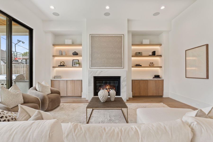 Anchored by a modern fireplace with a clean stone surround, the living space is framed by custom built-ins and warm wood cabinetry, offering both style and function.