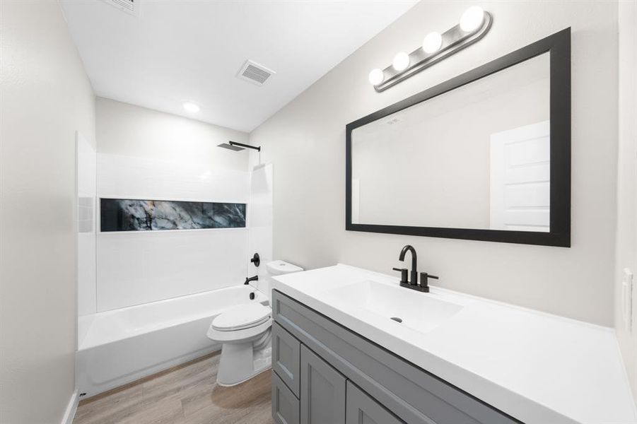 Bathroom featuring washtub / shower combination, vanity, and light wood finished floors Bathroom featuring washtub / shower combination, vanity, and light wood finished floors