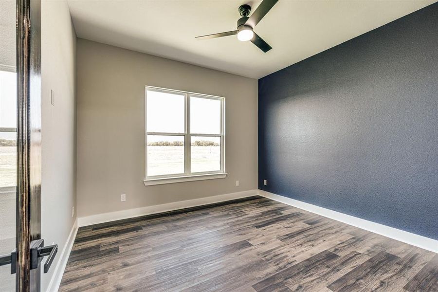 Empty room featuring ceiling fan and dark hardwood / wood-style floors