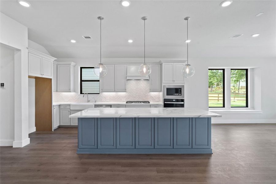 The generously sized center island features a breakfast bar, perfect for casual dining and entertaining. The island is beautifully designed with pristine quartz countertop and elegant pendant lights.