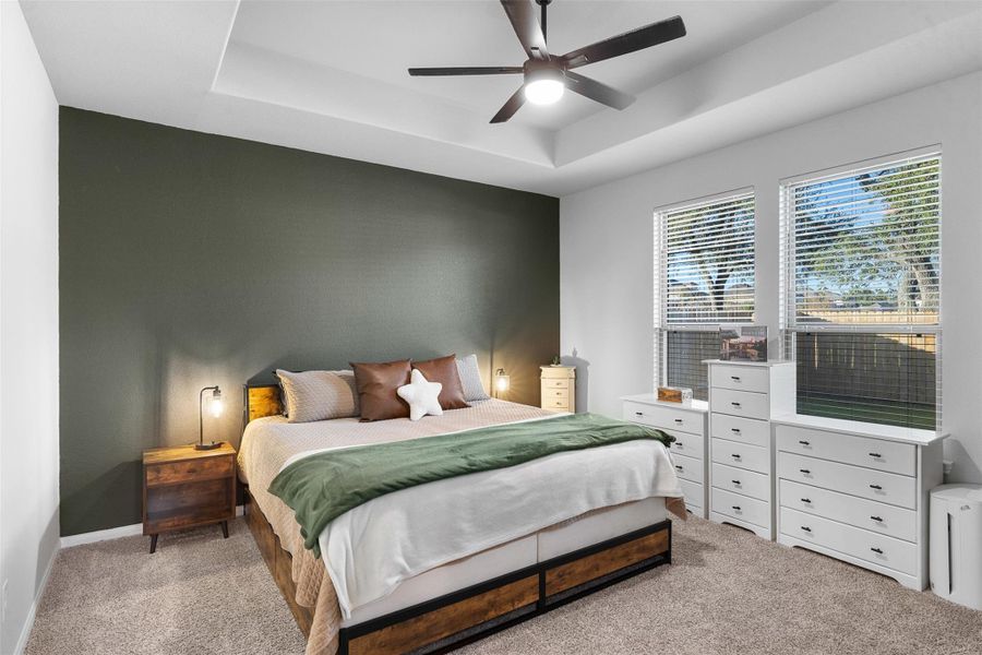 Tranquil and spacious primary bedroom featuring a stylish accent wall, ample natural light, and elegant design for your perfect retreat.