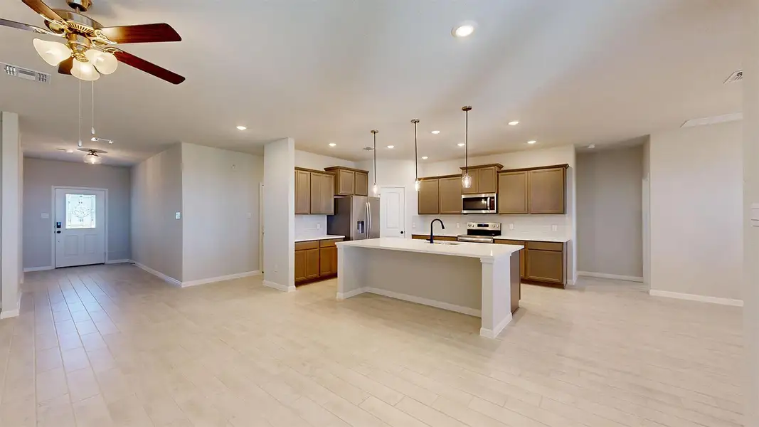 Kitchen with wood finish cabinetry, open floor plan, tasteful backsplash, and an island with sink