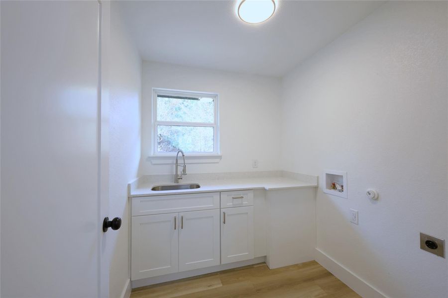 Landry room (located upstairs) with sink and folding area. Electric washer/dryer hook ups.