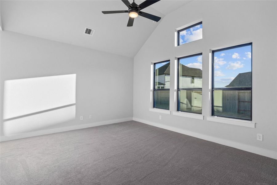 Relax and unwind after a long day in this impressive primary suite! This generously sized room offers plus carpet flooring, neutral-toned paint, high vaulted ceilings with a ceiling fan, and large windows for added comfort and tranquility.