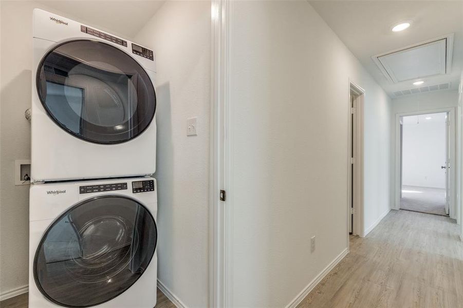 Clothes washing area featuring light hardwood / wood-style floors and stacked washer / dryer