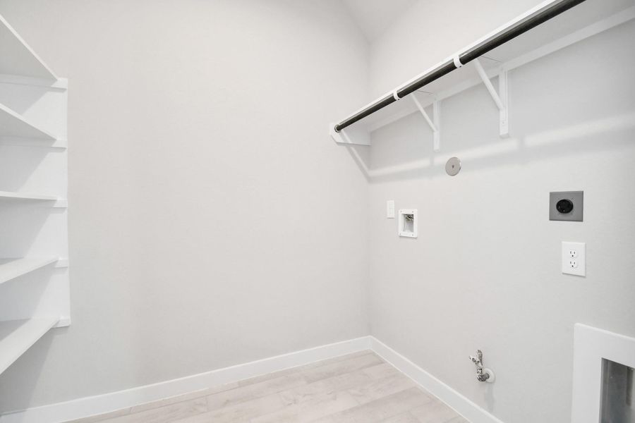 A perfect blend of functionality and comfort. Capture the essence of easy living with a first-floor laundry room, thoughtfully equipped with shelving for effortless organization. Both electric and gas connections available. Sample photo of completed home with similar floor plan. Actual colors and selections may vary.