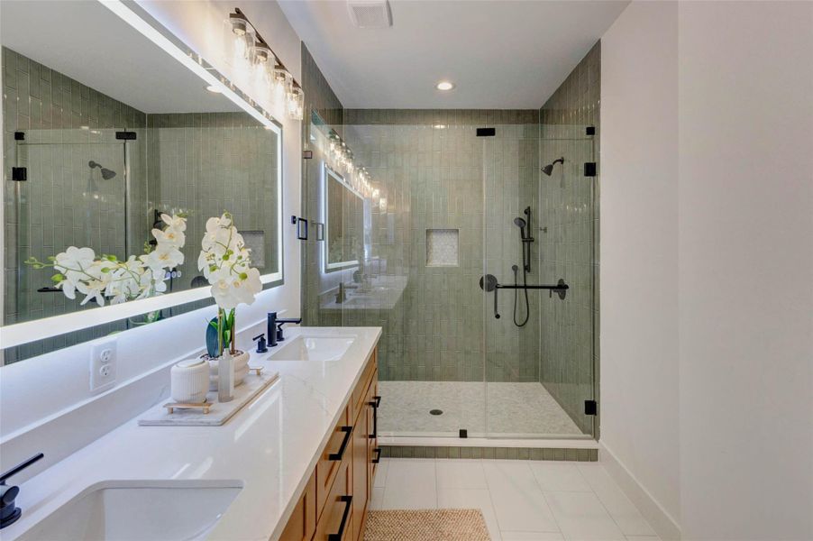 Luxurious en-suite with a spacious shower featuring dual shower heads and elegant custom tile work.