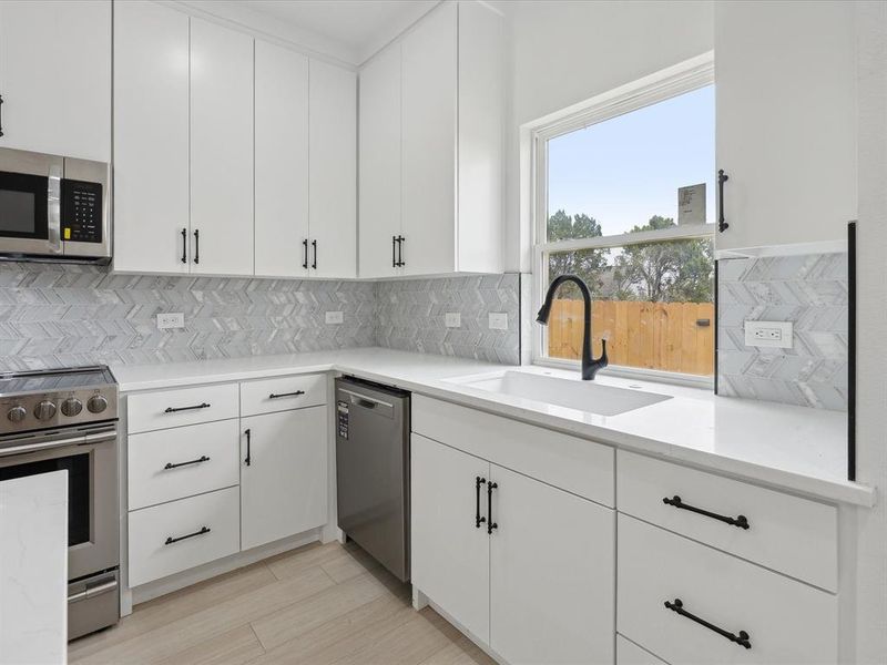 Kitchen with white cabinetry, sink, and appliances with stainless steel finishes