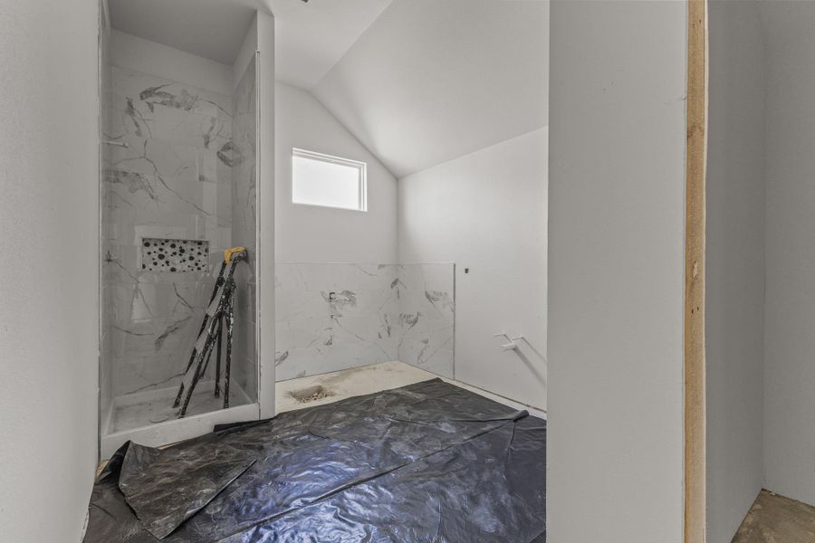 Marble-tiled shower with integrated shelving highlights this ready-to-finish bathroom.