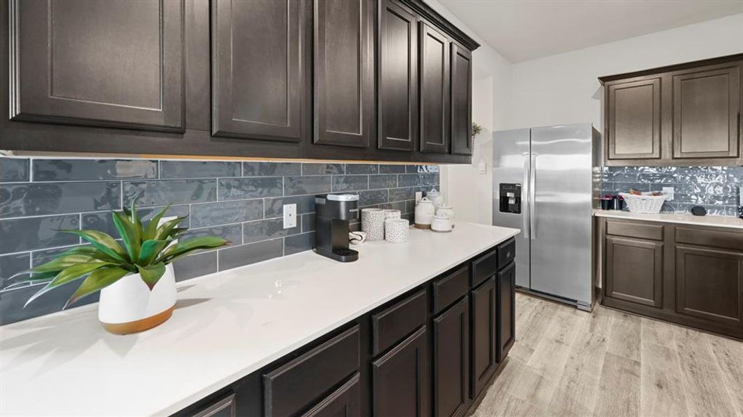 The kitchen features dark wood cabinetry, white countertops, and a gray subway tile backsplash