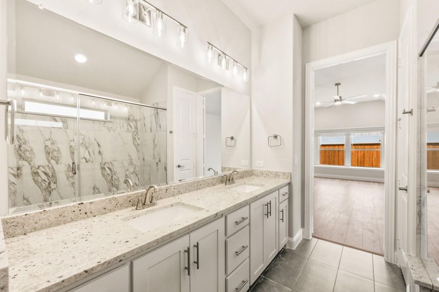 Ensuite bathroom with double vanity, granite countertops, marble tile shower, and large mirror with vanity lighting Ensuite bathroom with double vanity, granite countertops, marble tile shower, and large mirror with vanity lighting