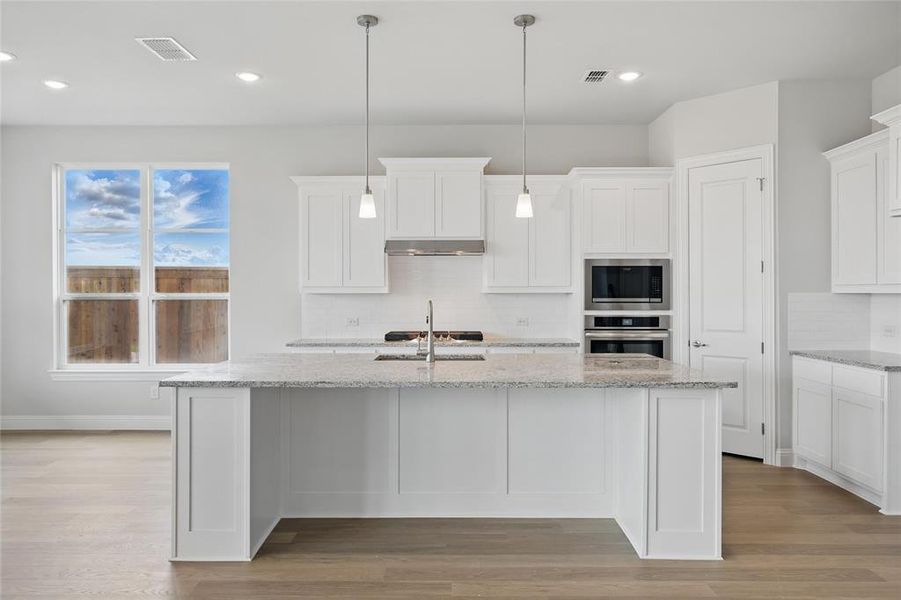 Kitchen featuring appliances with stainless steel finishes, backsplash, light wood finished floors, a sink, and recessed lighting