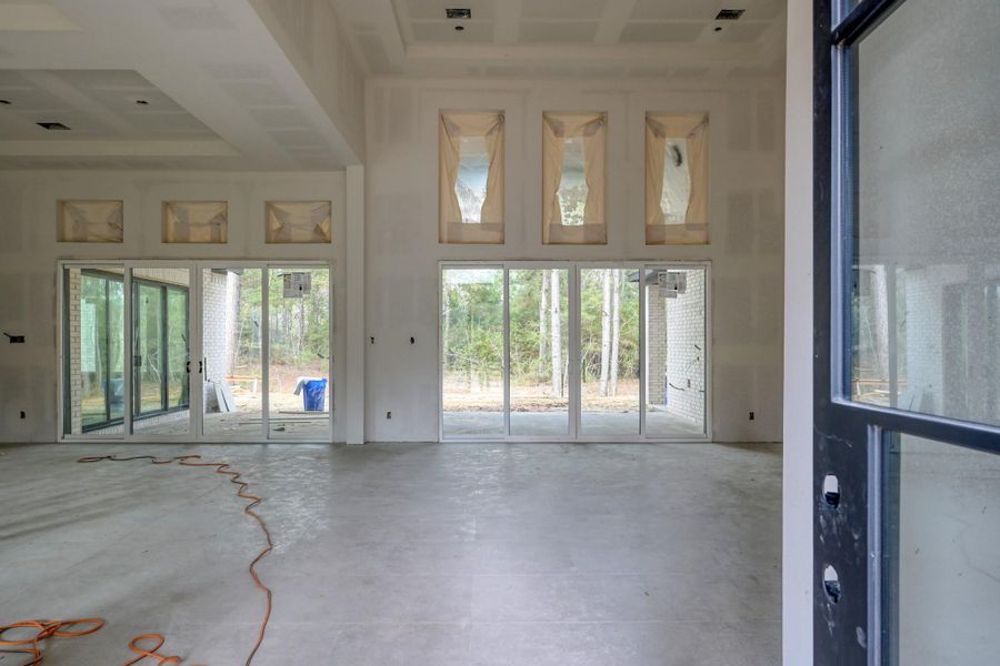 Rod iron doors open to soaring 16 foot ceilings and expansive windows, pre-wired for electric shades, frame peaceful outdoor views, filling the space with natural light and a calm, open feel.