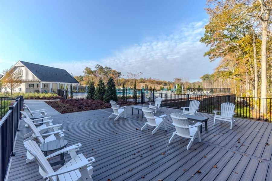 Adirondak chairs for resident use - large pool in the background, surround by natural tree border.