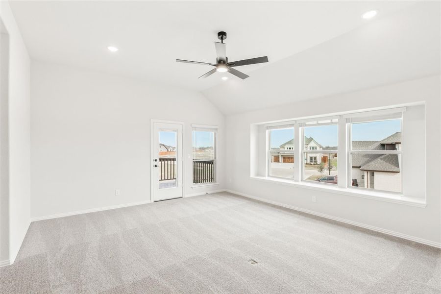 Empty room with vaulted ceiling, ceiling fan, carpet, large windows, and door to balcony Empty room with vaulted ceiling, ceiling fan, carpet, large windows, and door to balcony