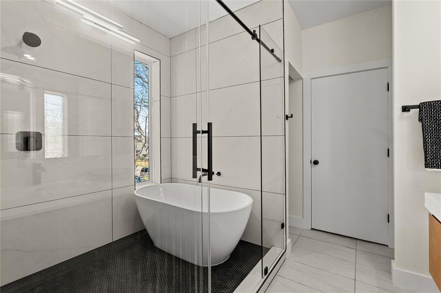 Bathroom with a soaking tub, tile walls, and vanity