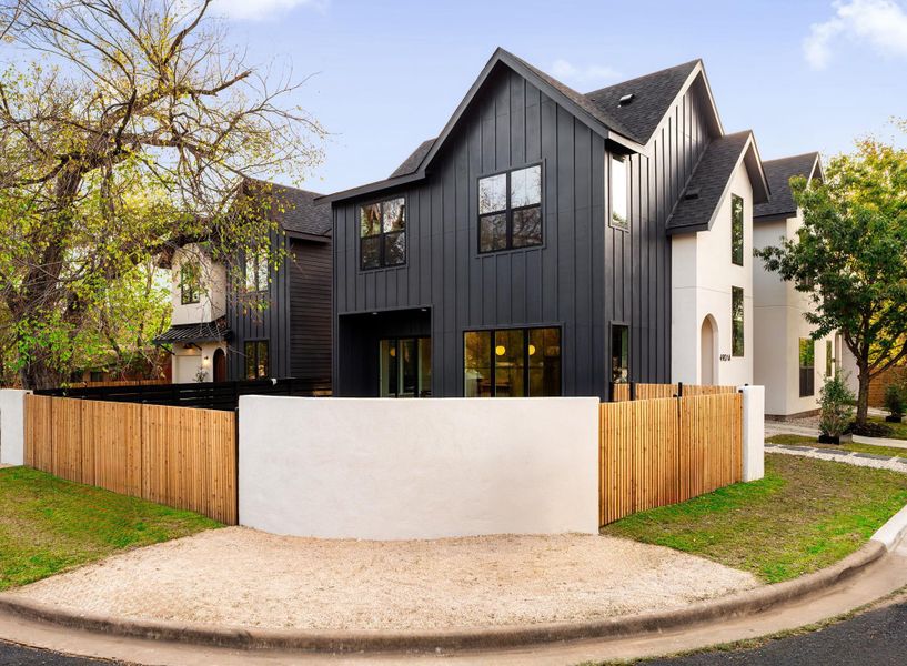 Modern farmhouse style home with board and batten siding, roof with shingles, and a fenced front yard