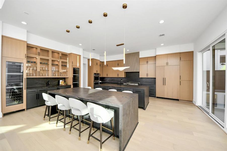 Sleek cabinetry, a large waterfall-edge island with ample seating, and high-end finishes throughout. The open design and integrated wine storage make it a perfect space for both cooking and entertaining.