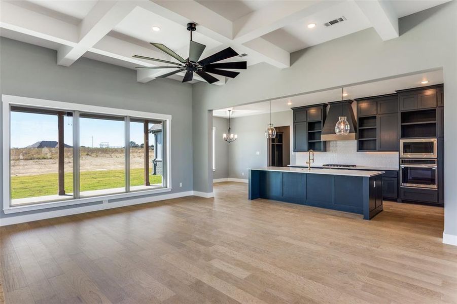 Kitchen with open floor plan, tasteful backsplash, an island with sink, hanging light fixtures, and beamed ceiling Kitchen with open floor plan, tasteful backsplash, an island with sink, hanging light fixtures, and beamed ceiling