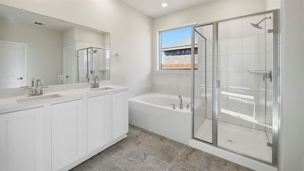 Full bathroom featuring double vanity, a garden tub, and a shower stall
