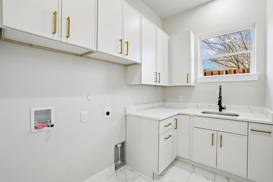Laundry area with electric dryer hookup, hookup for a washing machine, cabinet space, light marble finish floors, and gas dryer hookup
