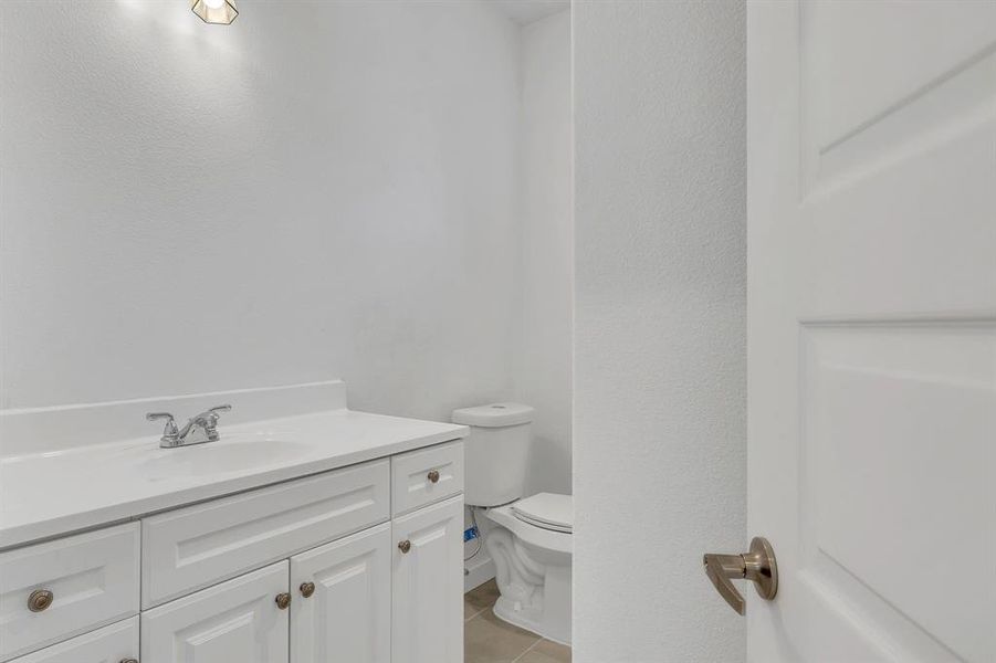 Bathroom featuring vanity, light tile patterned floors, and a textured wall