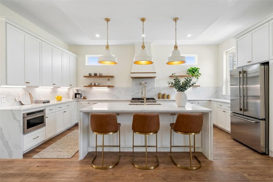 Virtually Staged - Chef's kitchen featuring quartz countertops, stainless steel appliances, a pot filler, statement pendant lighting, and an oversized waterfall island shown with a suggested seating arrangement. Virtually Staged - Chef's kitchen featuring quartz countertops, stainless steel appliances, a pot filler, statement pendant lighting, and an oversized waterfall island shown with a suggested seating arrangement.