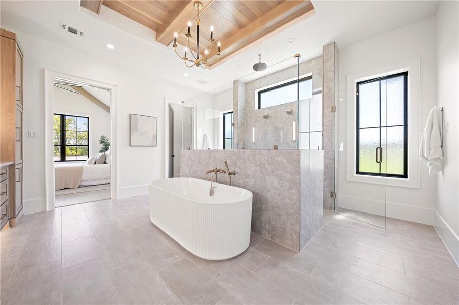 Ensuite bathroom with plenty of natural light, a freestanding tub, a shower stall, a wooden ceiling with exposed beams, and a chandelier