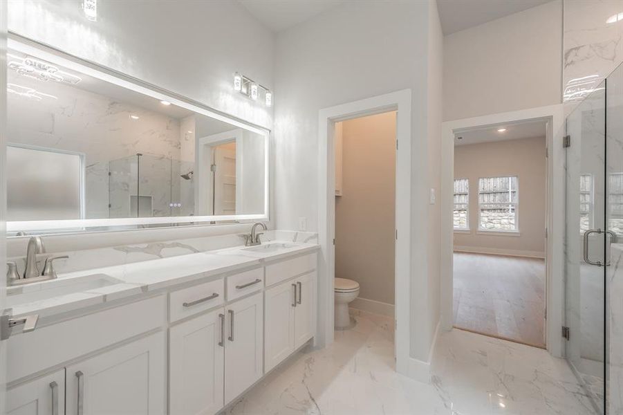 Full bath with light marble finish flooring, double vanity, a marble finish shower, and recessed lighting
