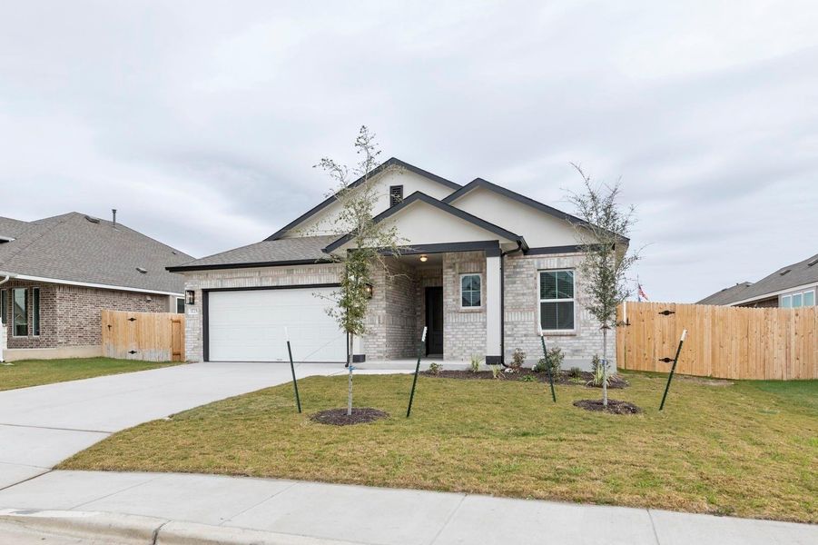 View of front of property featuring brick siding, a gate, driveway, and a garage