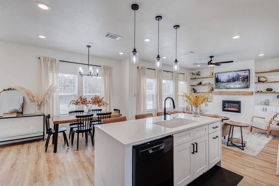 Kitchen with sink, hanging light fixtures, black dishwasher, an island with sink, and white cabinets Kitchen with sink, hanging light fixtures, black dishwasher, an island with sink, and white cabinets