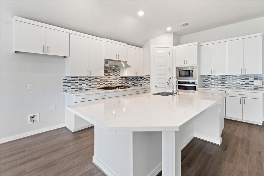 Kitchen with white cabinetry, a center island with sink, light stone countertops, a breakfast bar area, and recessed lighting