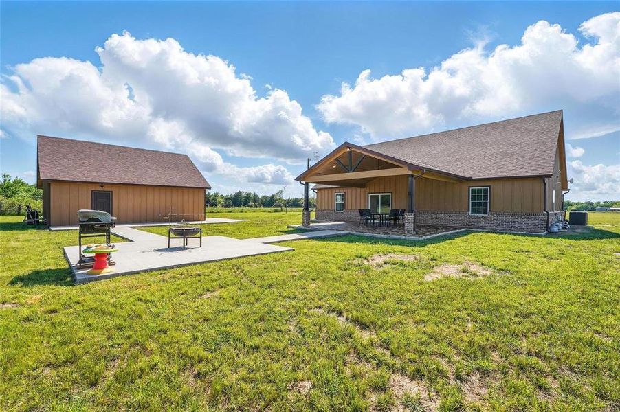 Back of property featuring a patio area, board and batten siding, a yard, and a fire pit Back of property featuring a patio area, board and batten siding, a yard, and a fire pit
