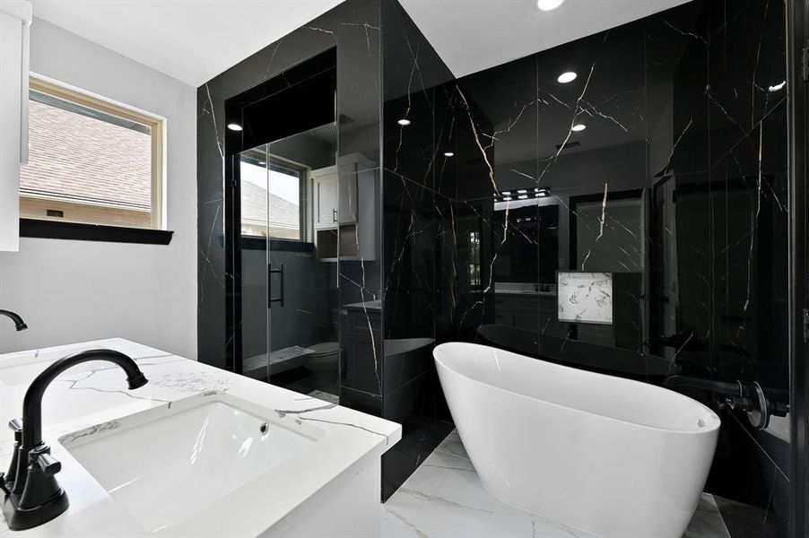 Step into the stunning primary bathroom with modern finishes, where white floor tiles contrast beautifully with luxurious black tiles adorned with gold details on the shower and soaking tub wall from floor to ceiling.