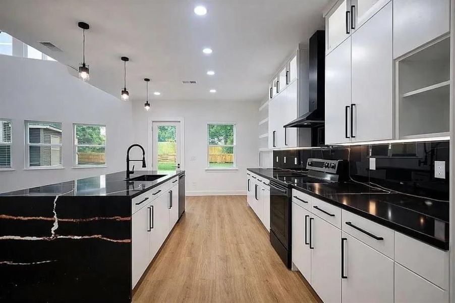 Contemporary kitchen featuring a large island with black countertop and white cabinetry