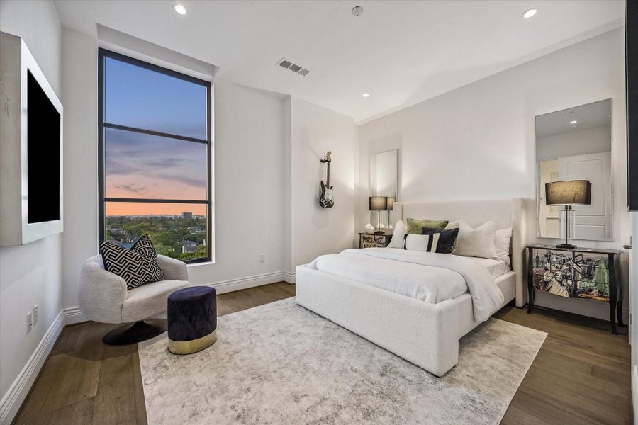 The secondary bedroom is bright & inviting, featuring warm wood flooring, clean lines & a large window that frames beautiful treetop & skyline views. A comfortable layout offers flexibility for guests, while the soft finishes & natural light create a relaxing retreat.