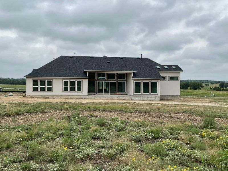 Back of property with a shingled roof, a patio, and stucco siding