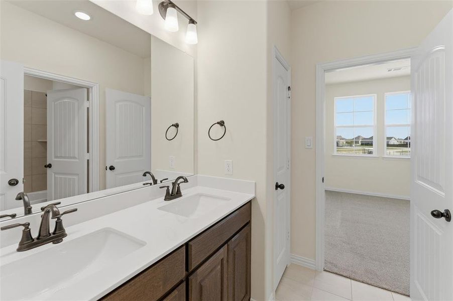 Bathroom with double vanity, light colored carpet, and light tile patterned floors Bathroom with double vanity, light colored carpet, and light tile patterned floors