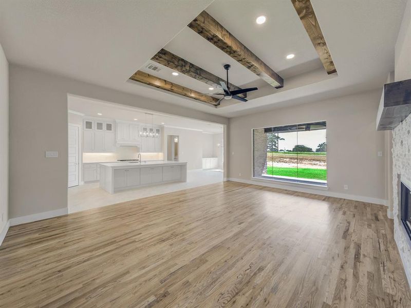 Unfurnished living room with a chandelier, a fireplace, light wood-type flooring, recessed lighting, and beam ceiling Unfurnished living room with a chandelier, a fireplace, light wood-type flooring, recessed lighting, and beam ceiling